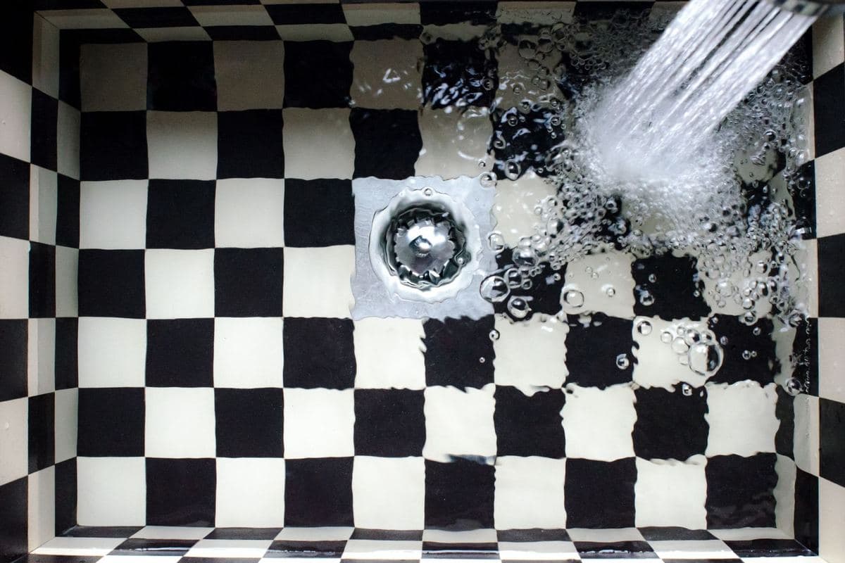 Overhead view of a kitchen sink with water running into the drain