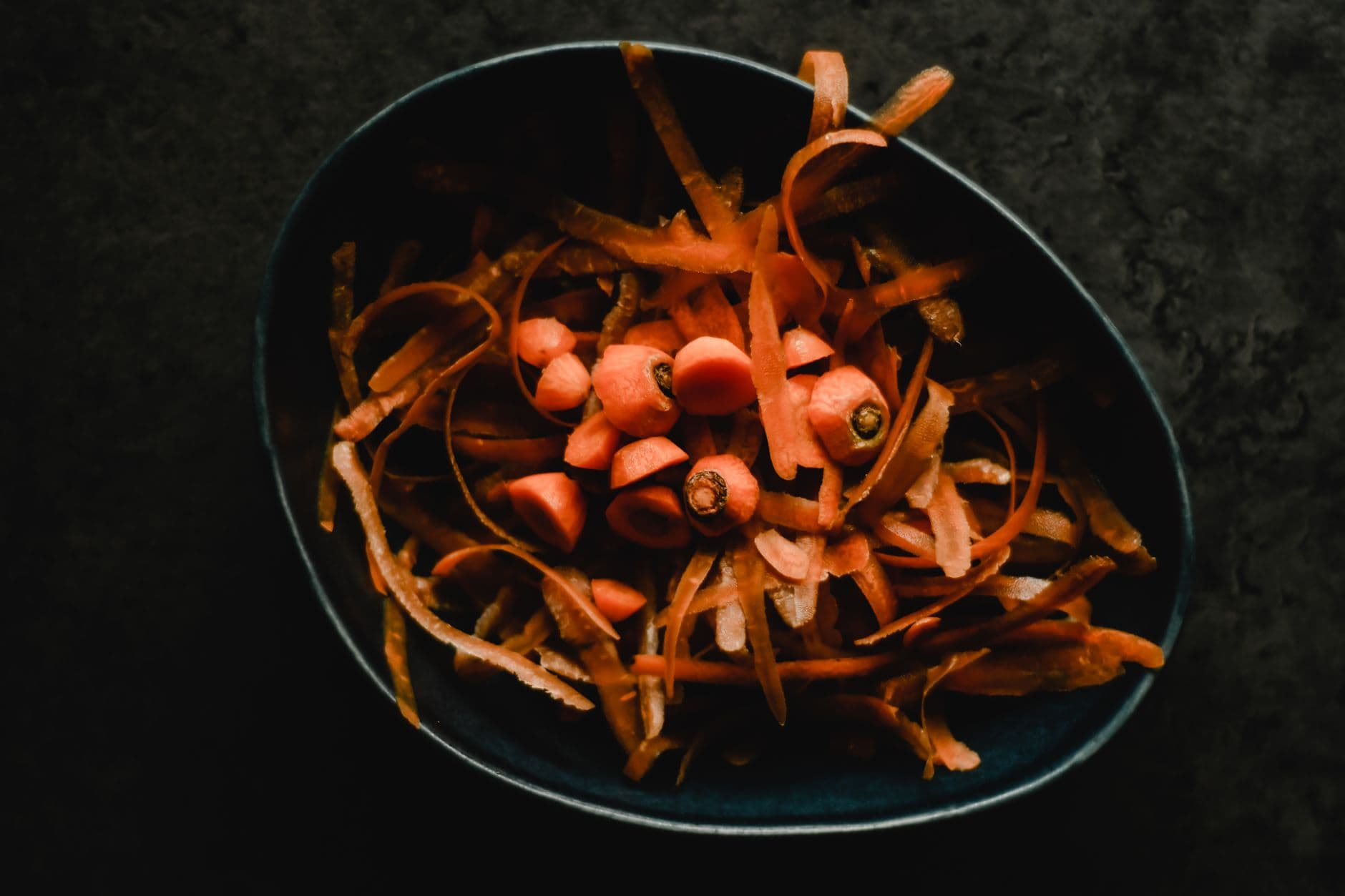 Close view of fresh carrot peelings and vegetable scraps in a bowl