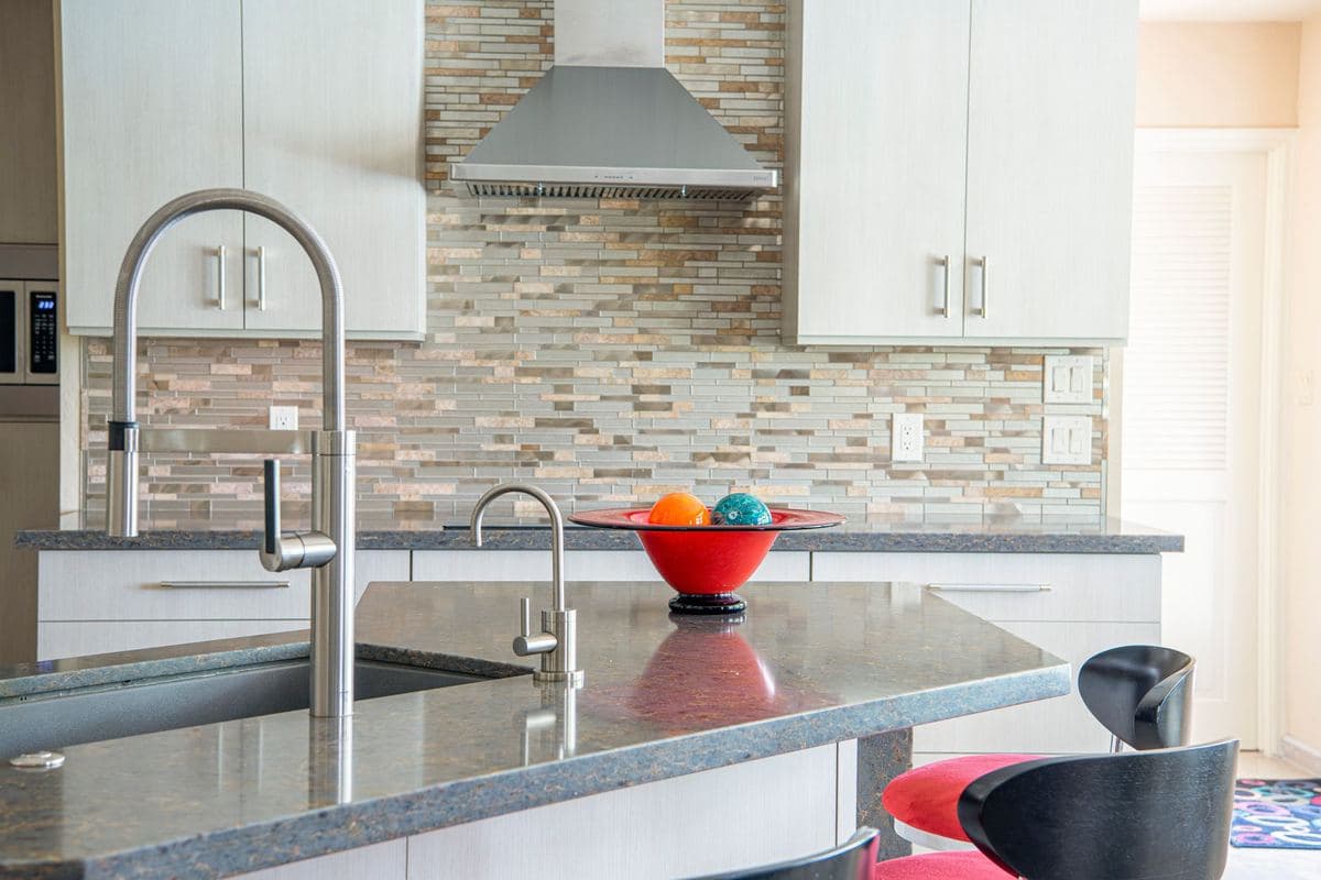 Gooseneck kitchen faucet over a sink on a stone countertop
