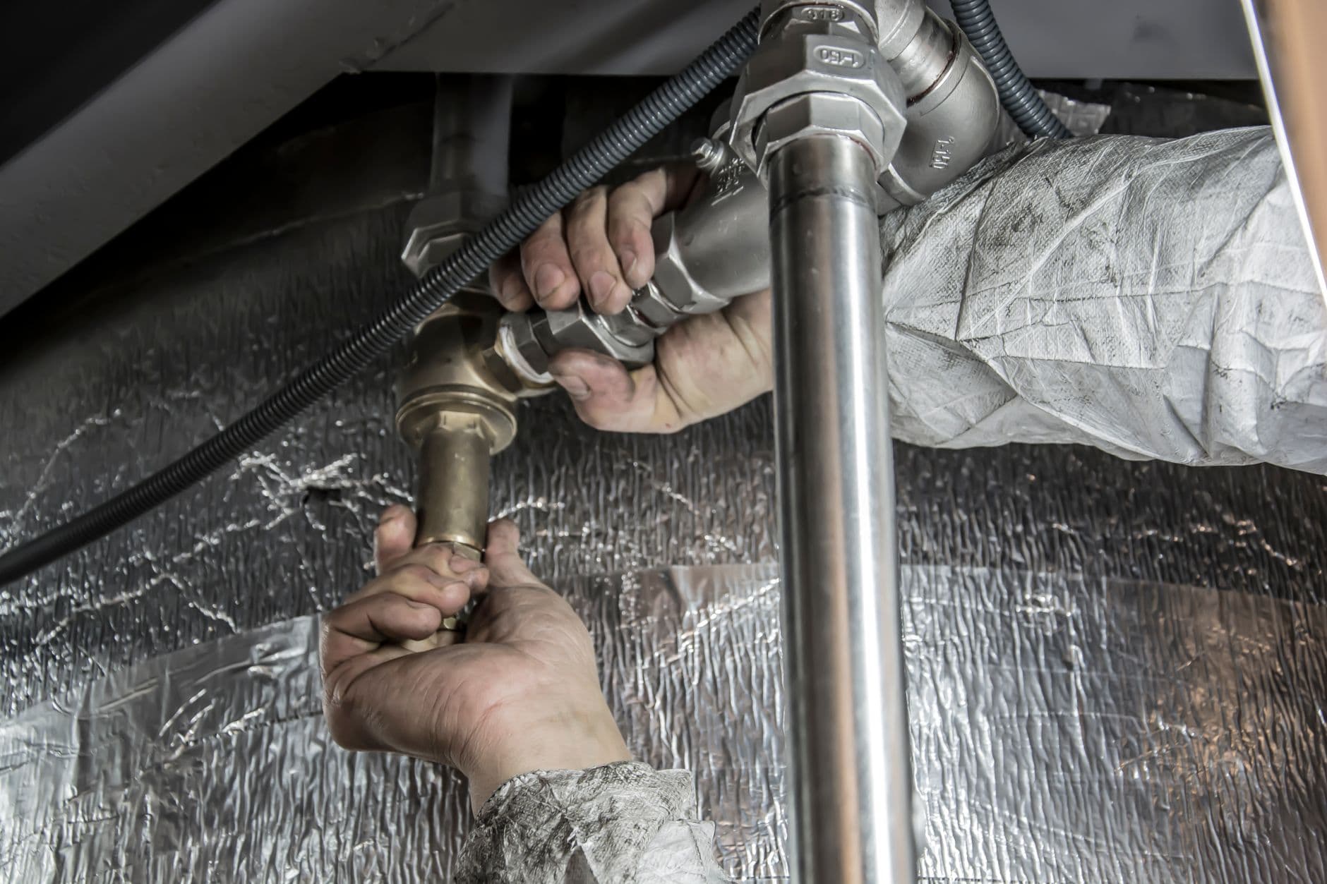 Hands fitting a compression supply connection under a sink cabinet