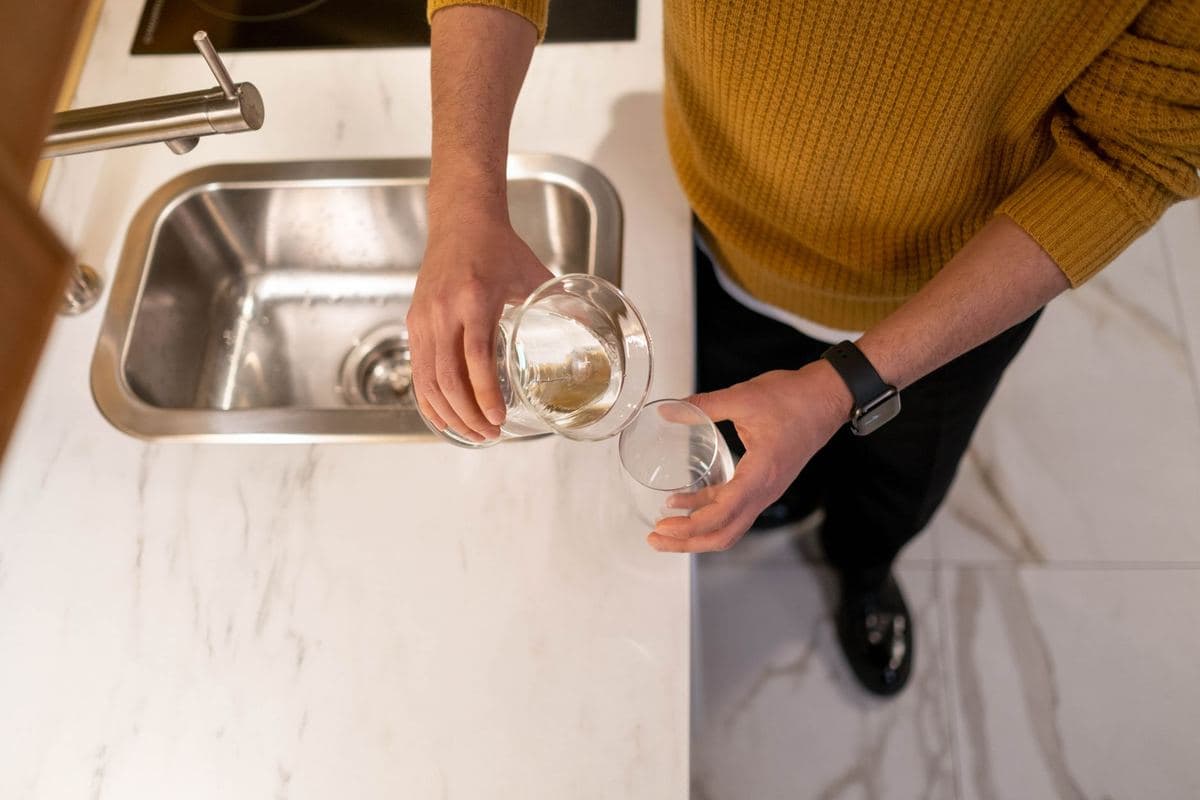 Water pouring from a kitchen faucet into a glass