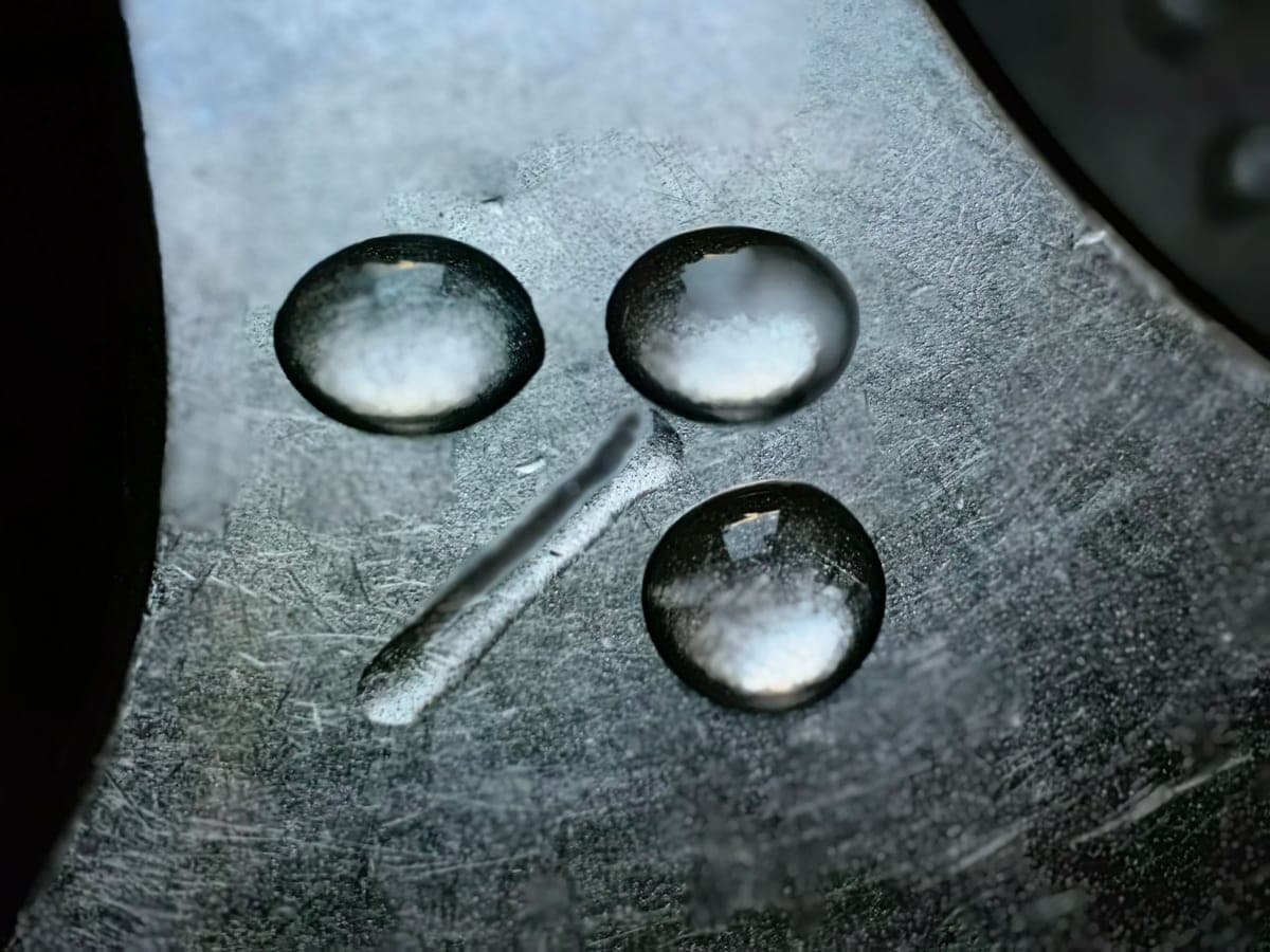 Water droplets and limescale marks drying on a metal surface