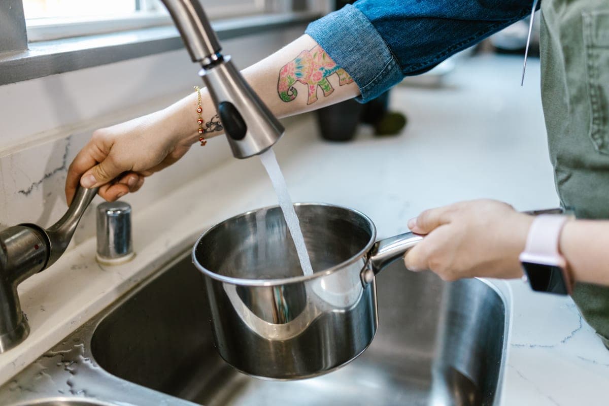 Tall kitchen faucet filling a large pot in a deep sink