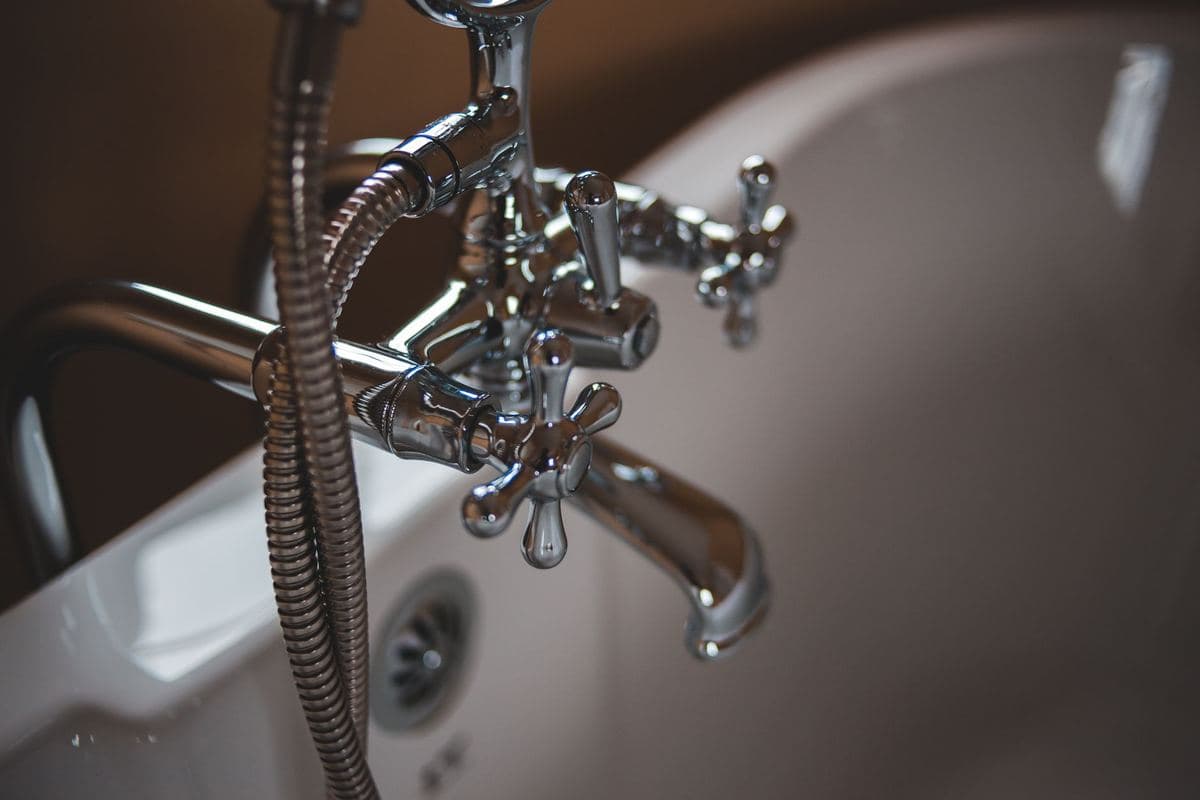 Polished chrome faucet spout reflecting a kitchen window