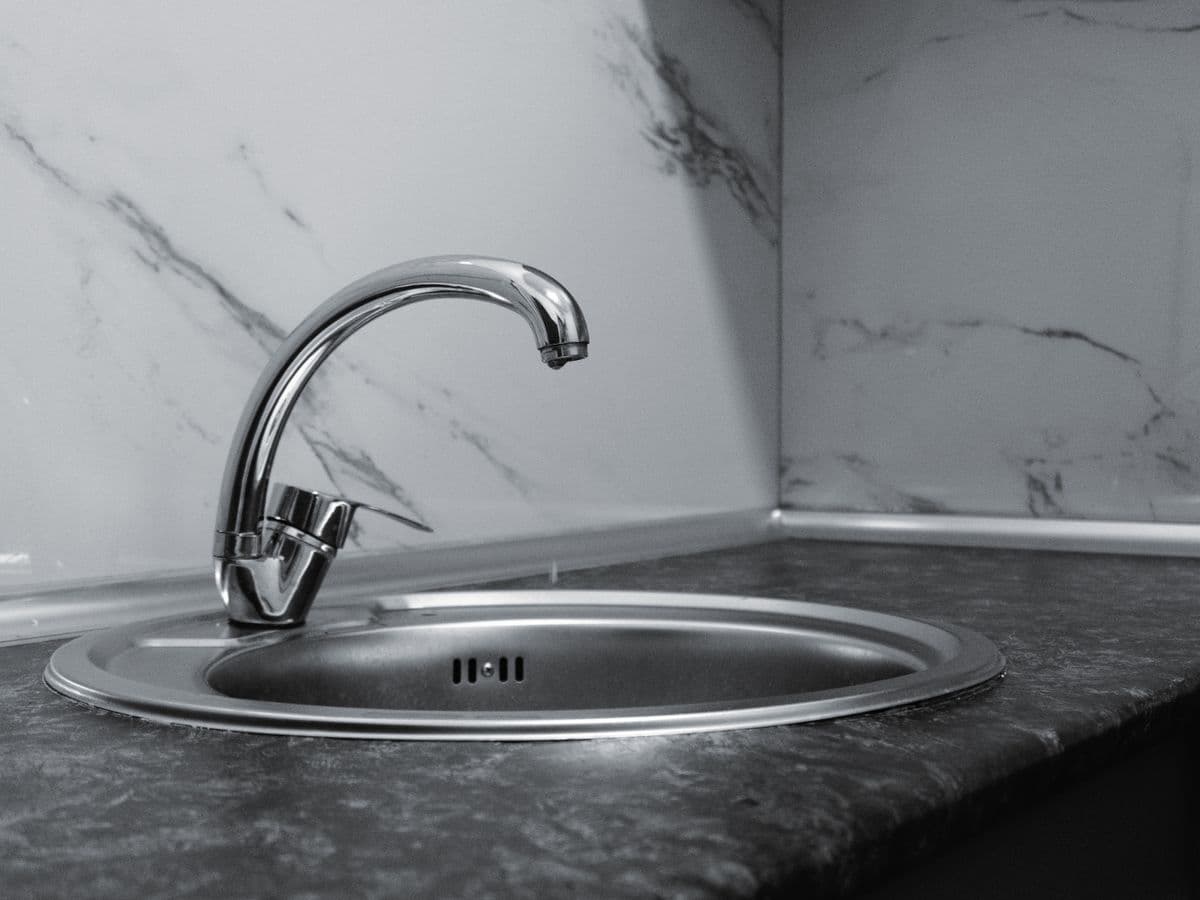 Single-handle stainless kitchen faucet against a marble backsplash