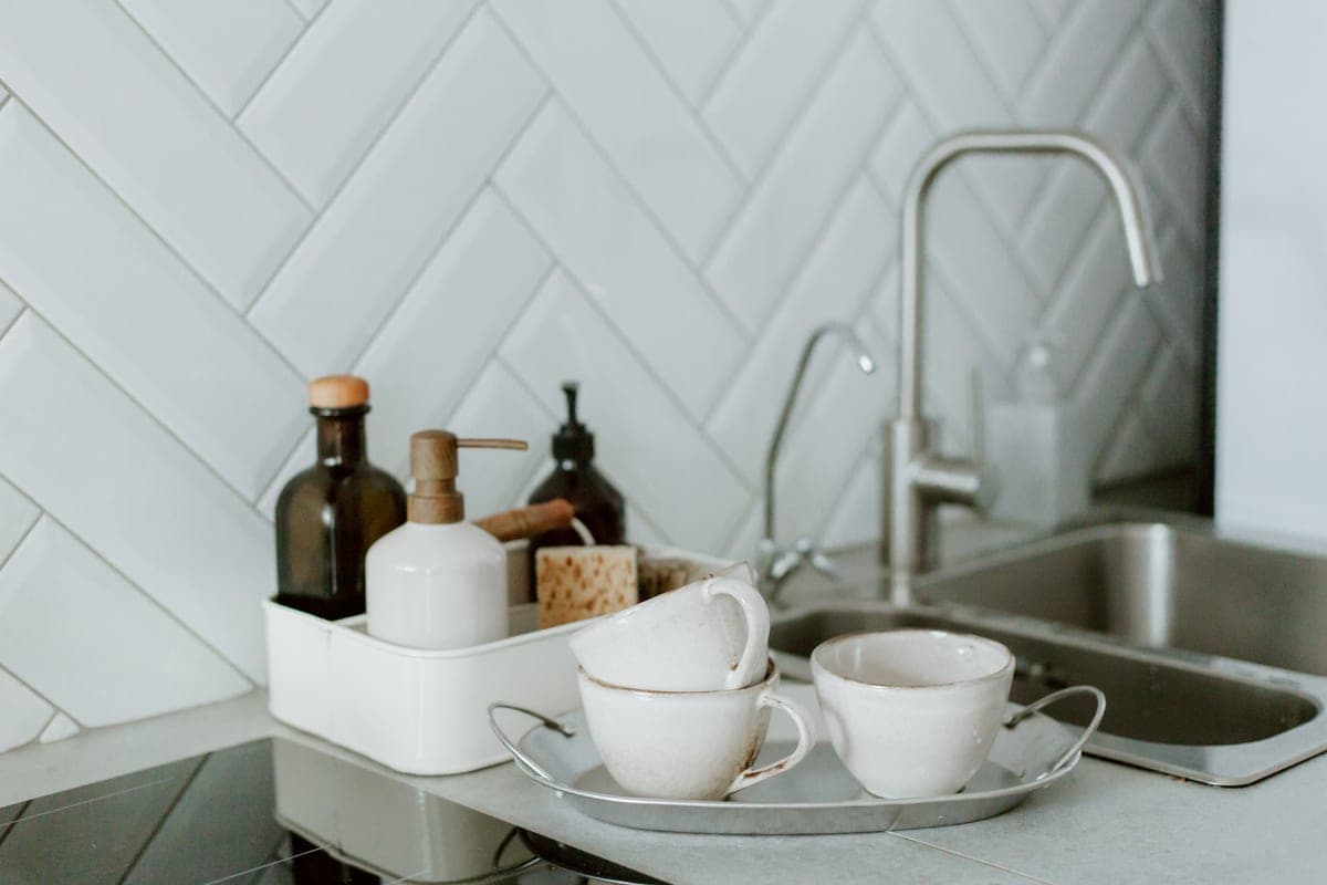 Soap dispenser beside a kitchen faucet on a sink deck