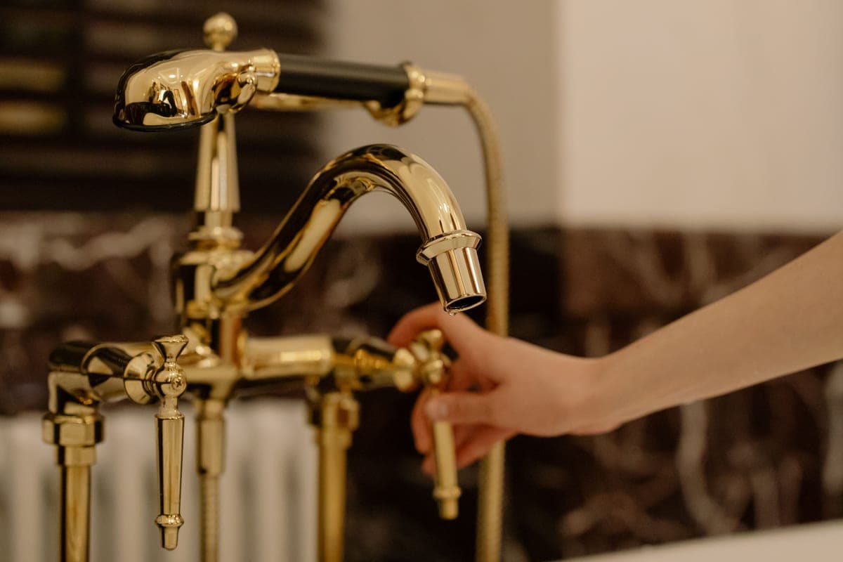 Hand tapping the spout of a kitchen faucet to start the water