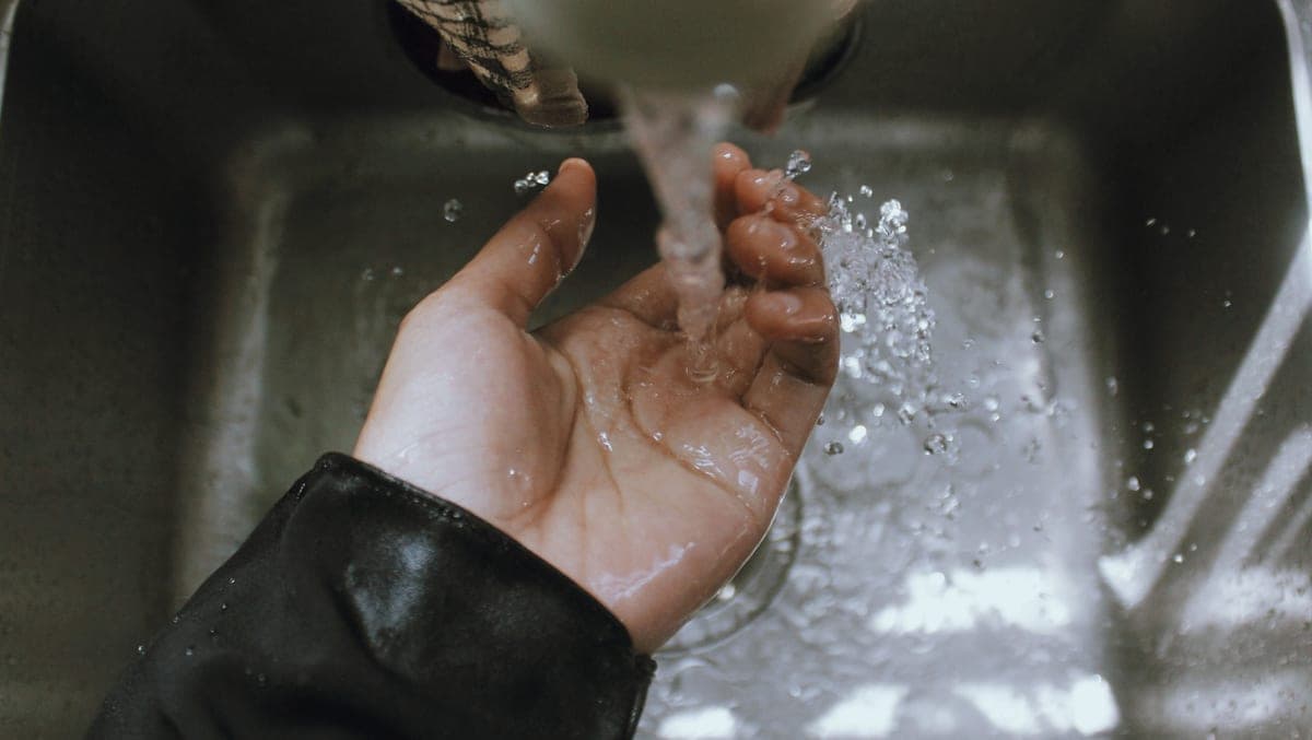 Hand held beneath a touchless kitchen faucet with water flowing