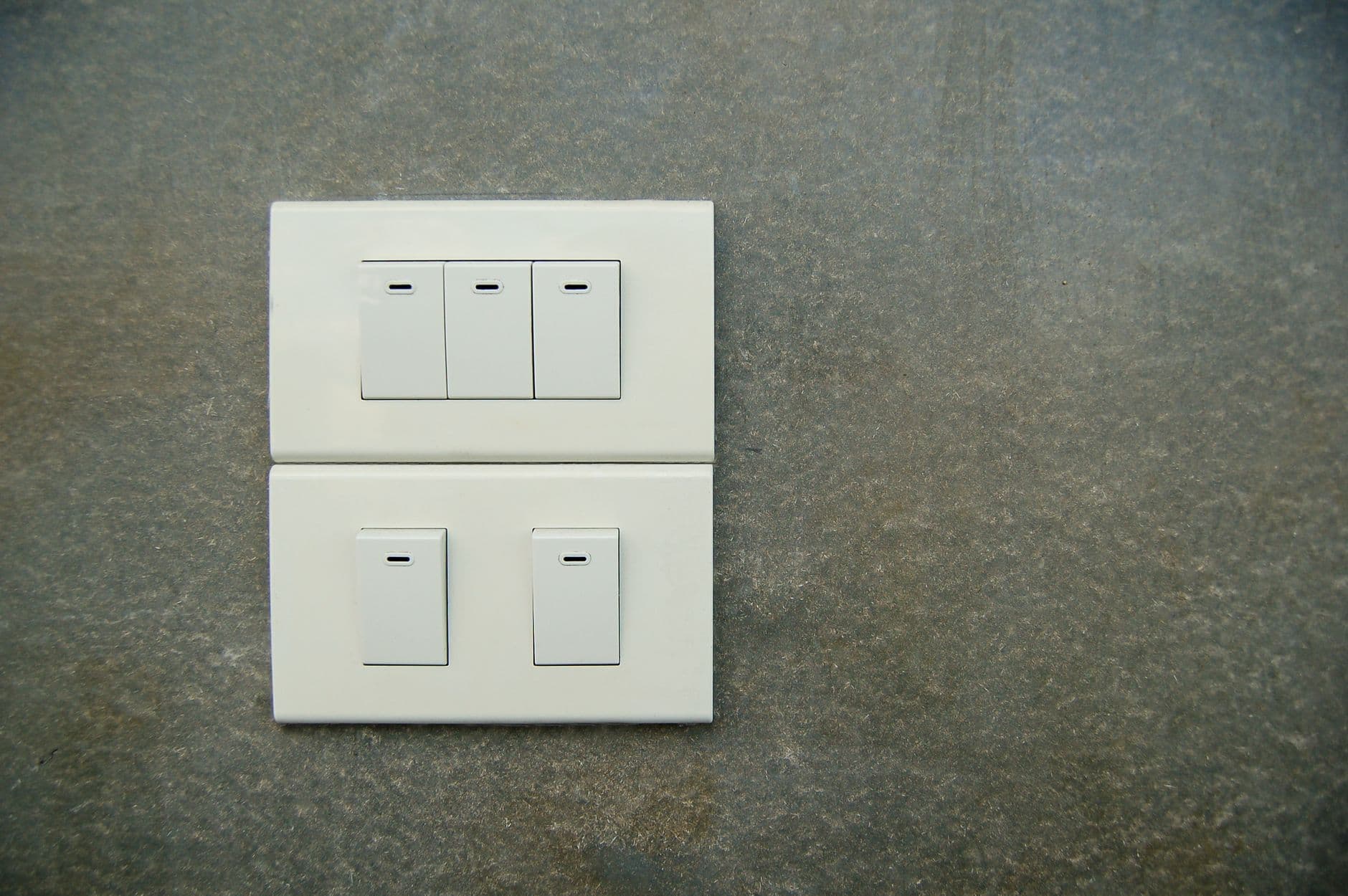 White rocker light switches mounted on a textured wall