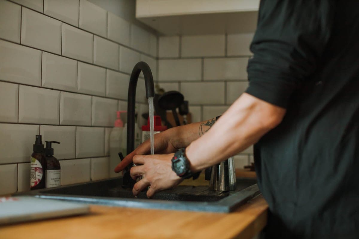 Person fitting a new kitchen faucet at a sink