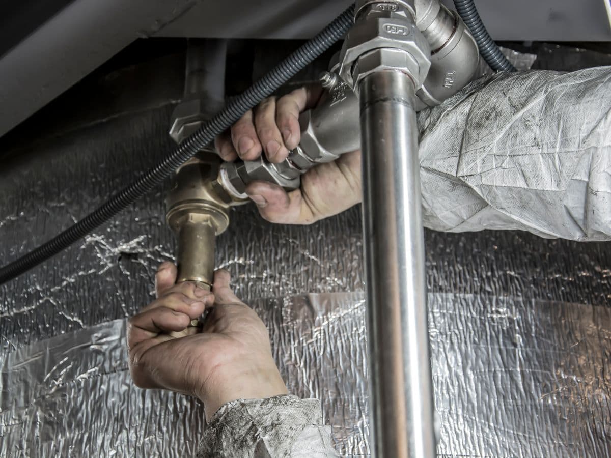 Close-up of hands working on pipework under a sink