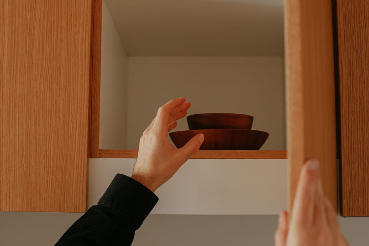 Hand reaching into the cabinet beneath a kitchen sink