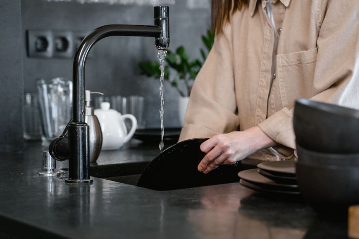 Person washing dishes at a kitchen sink