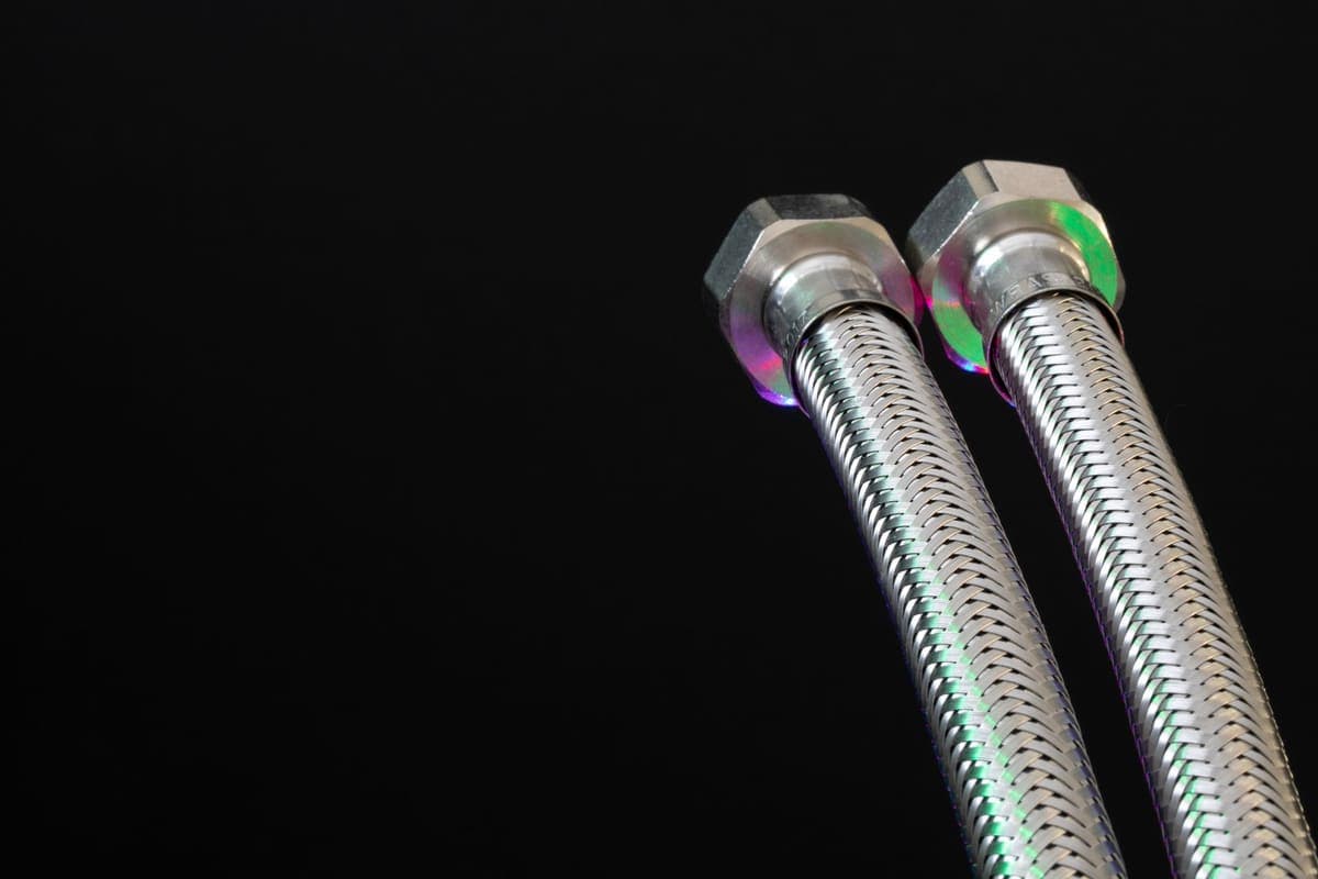 Braided stainless steel water supply hose coiled on a surface