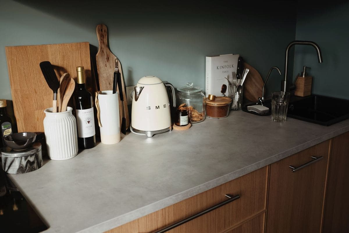 Wooden butcher block kitchen counter with utensils and a kettle