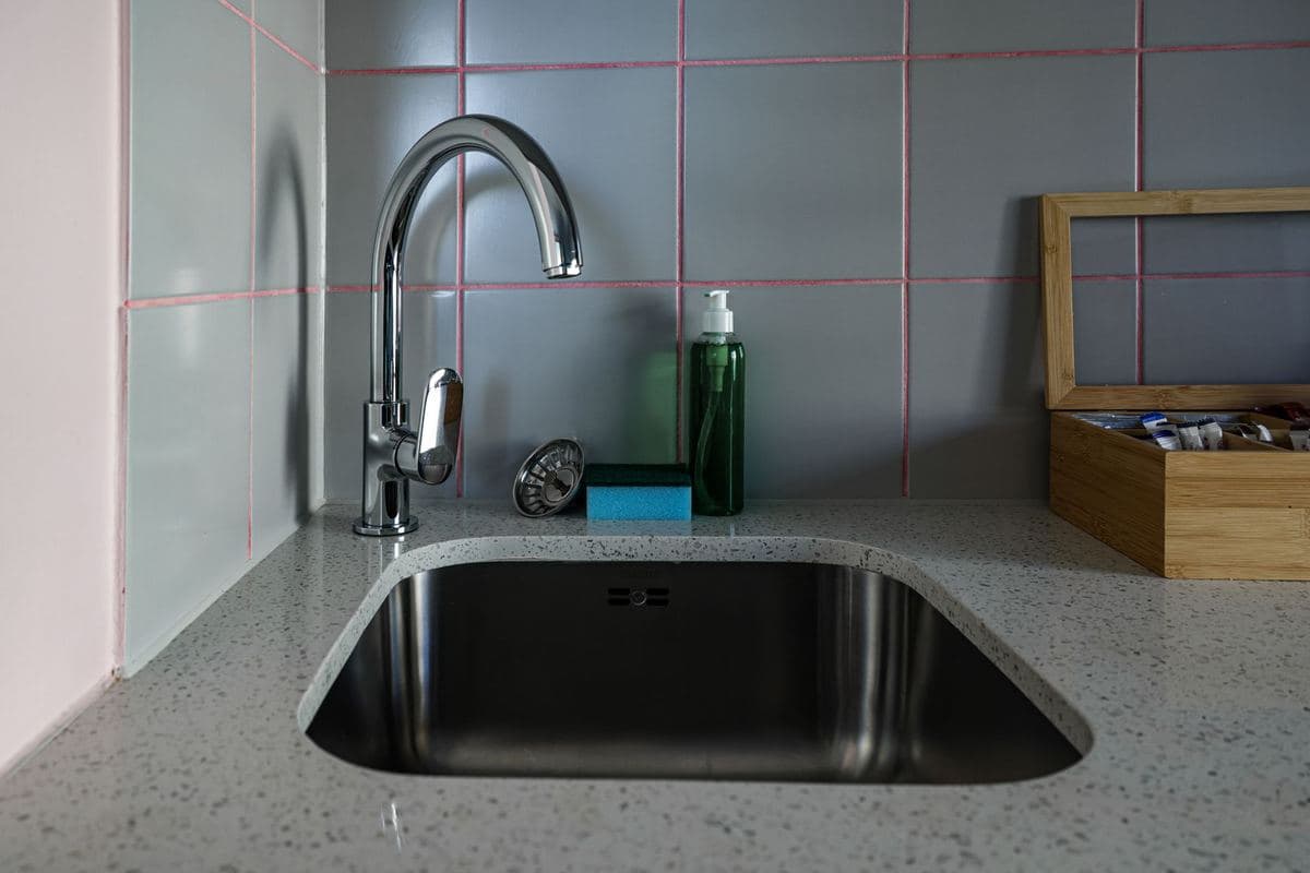 Modern kitchen sink and faucet set into a stone countertop