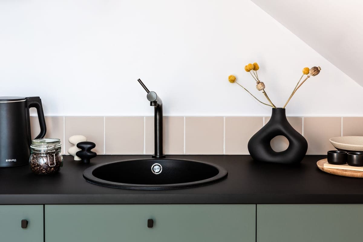 Dark granite composite kitchen sink beside a light stone countertop