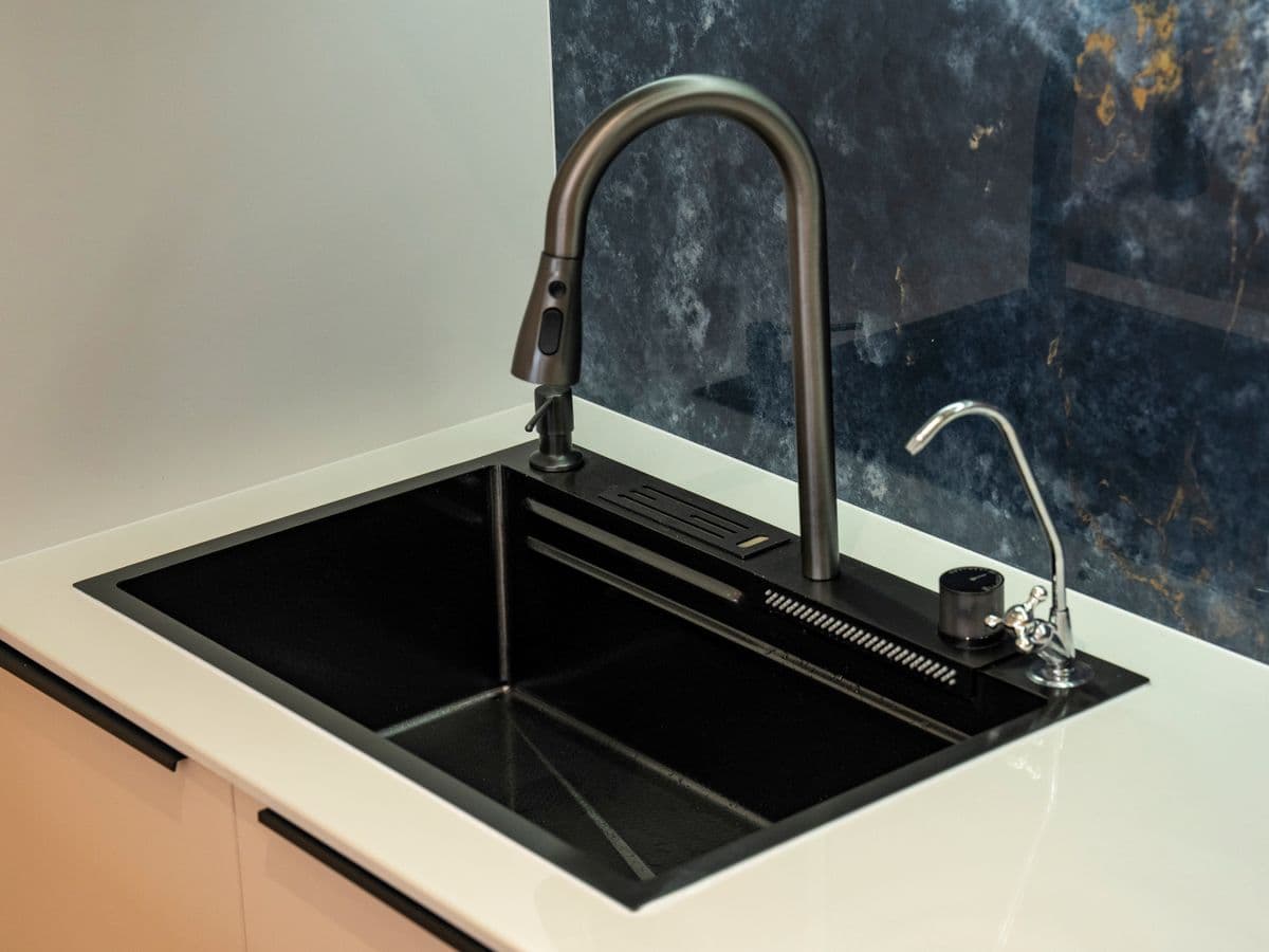 Single-bowl kitchen sink with a modern faucet against a marble backsplash