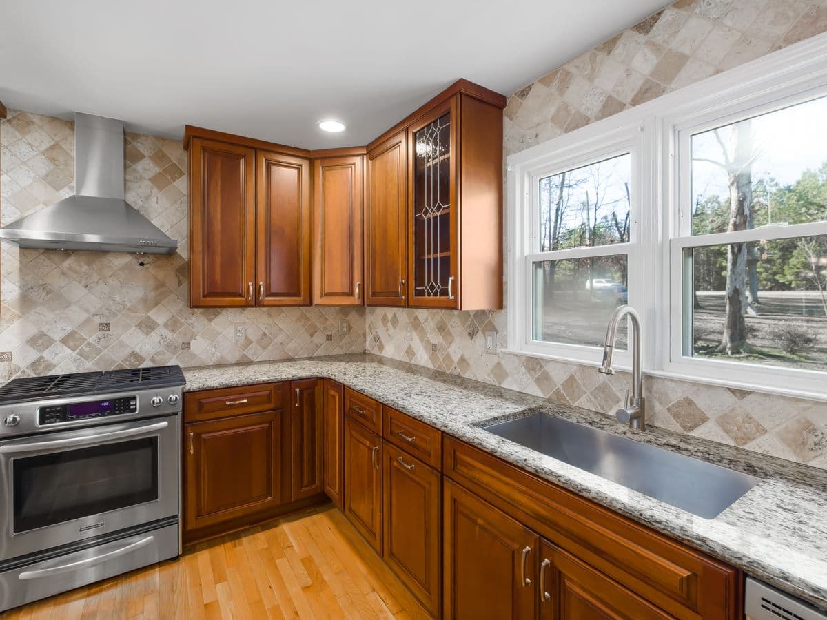 Stainless steel kitchen sink under a window in a granite countertop