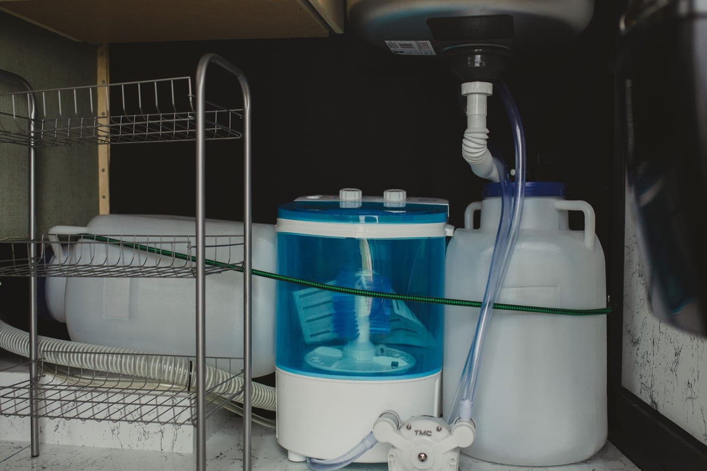 Plumbing and disposal fittings inside a cabinet beneath a kitchen sink