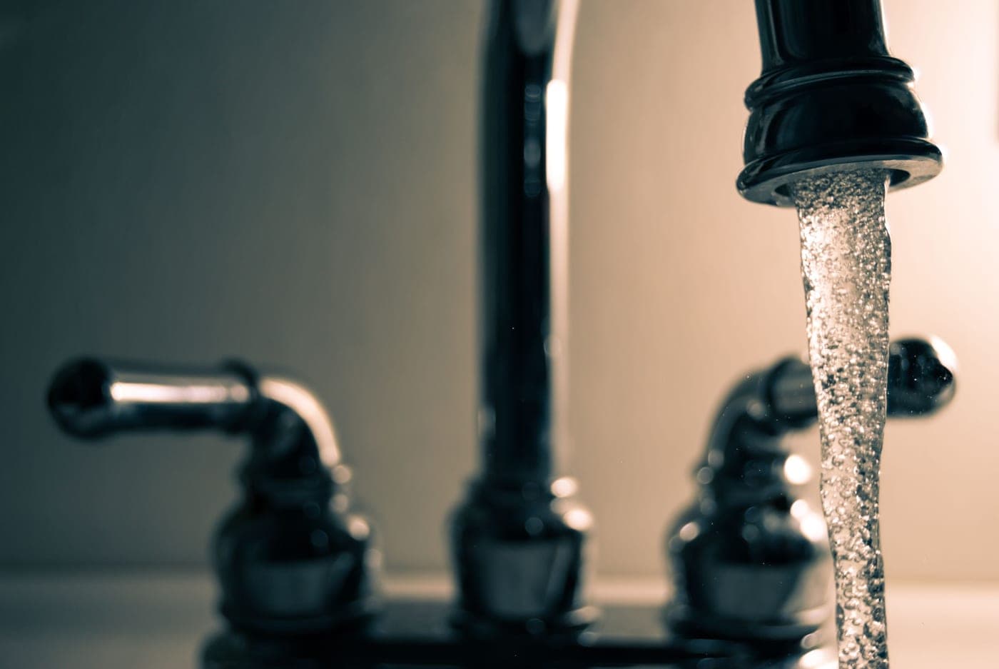 Close crop of a modern kitchen faucet neck above a stainless sink
