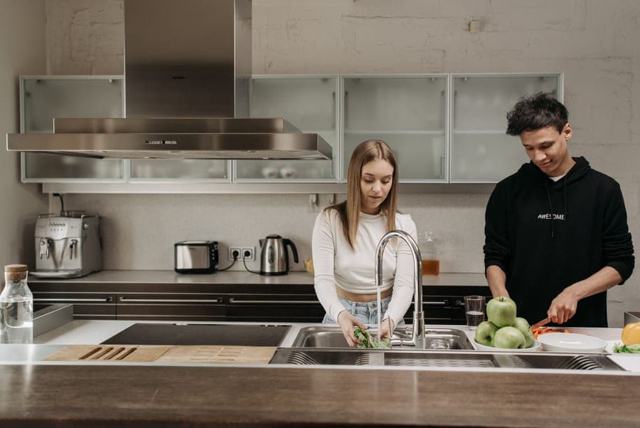 Hand tapping the spout of a touch-activated kitchen faucet