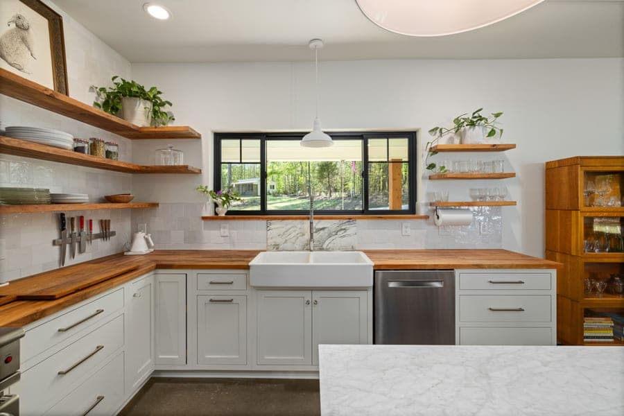 White enameled apron-front farmhouse sink set into wood cabinetry