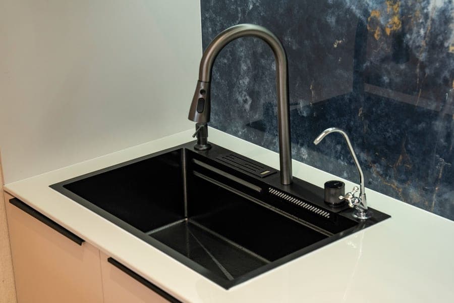 Stainless workstation sink with a cutting board sliding on its integrated ledge