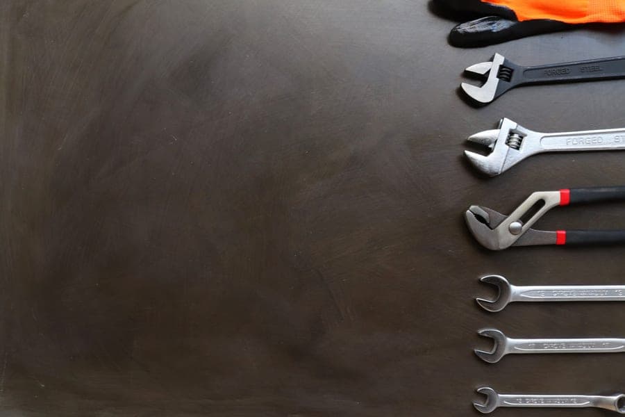 Basin wrench and hand tools laid out on a work surface